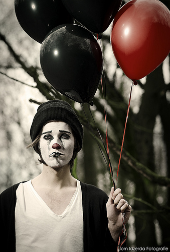 sad mime holding onto balloons
